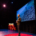 TJ stands on the TEDx stage with a photo of a foggy clearcut in the background.